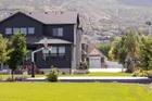 The 72 inch hoop on a court beside a dark timber house, with mountains behind, giving a sense of its height against a two storey building.