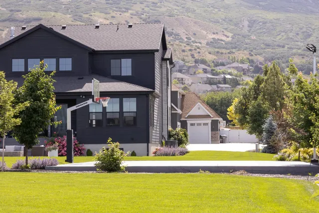 The 72 inch hoop on a court beside a dark timber house, with mountains behind, giving a sense of its height against a two storey building.