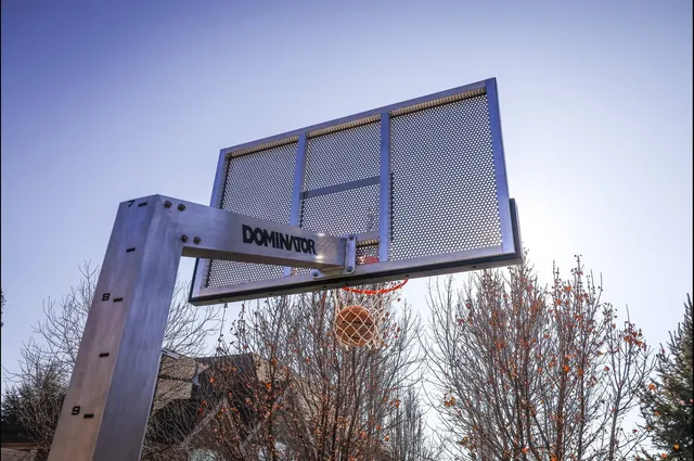 Looking up at an installed 72 Pro against a bright sky, close enough to see the perforations across the whole board and the Dominator wordmark on the arm.