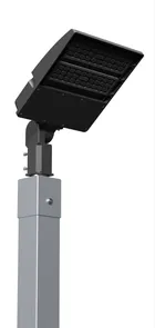 Close on the head of a single fixture pole, where the LED panel tilts on its bracket at the top of the square aluminum post.