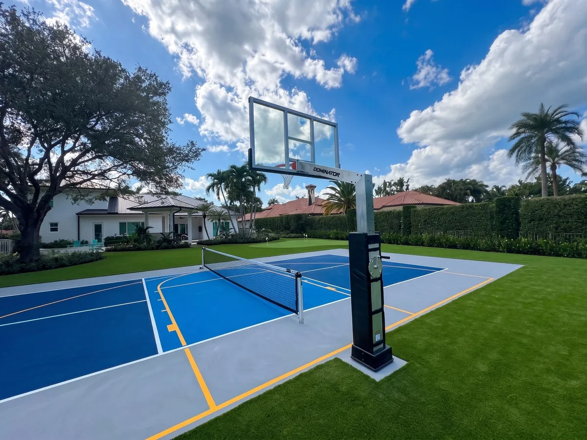 The 72″ glass adjustable hoop installed on a Jupiter sport court, backboard raised over blue and grey pickleball lines