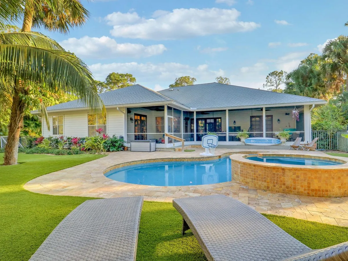 Home exterior with pool, spa, and manicured turf lawn