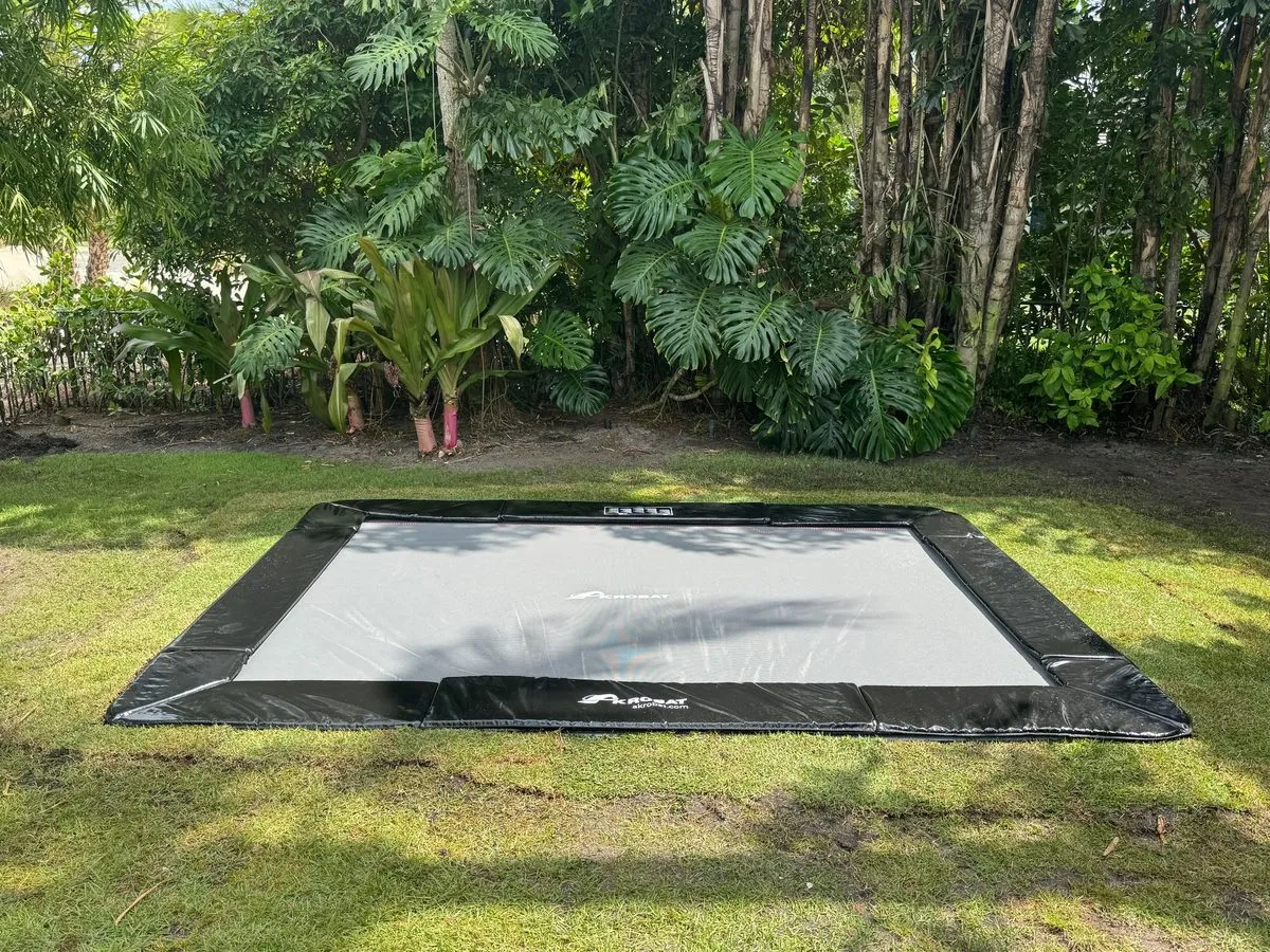 Rectangular in-ground trampoline in a shaded lawn