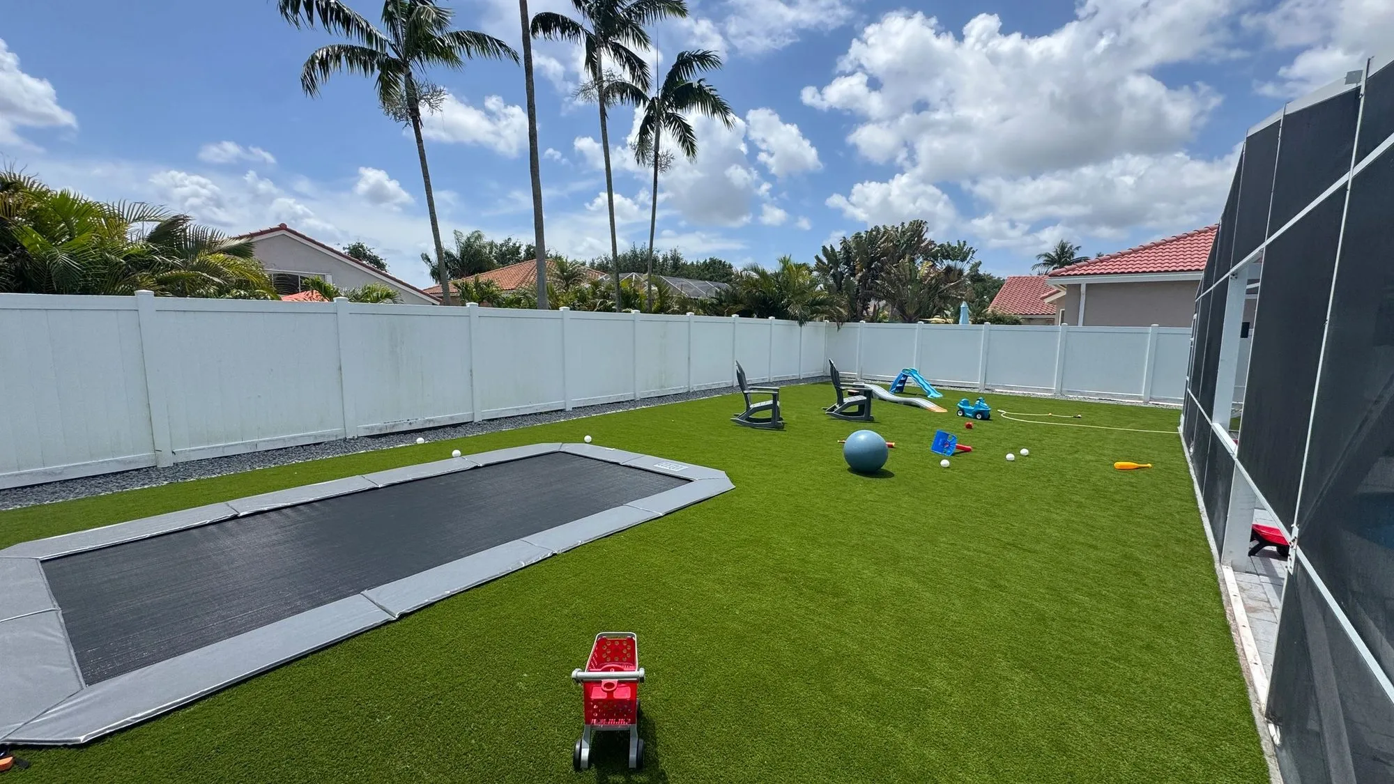 Backyard with a green sport court, basketball goal, artificial turf and an in-ground trampoline