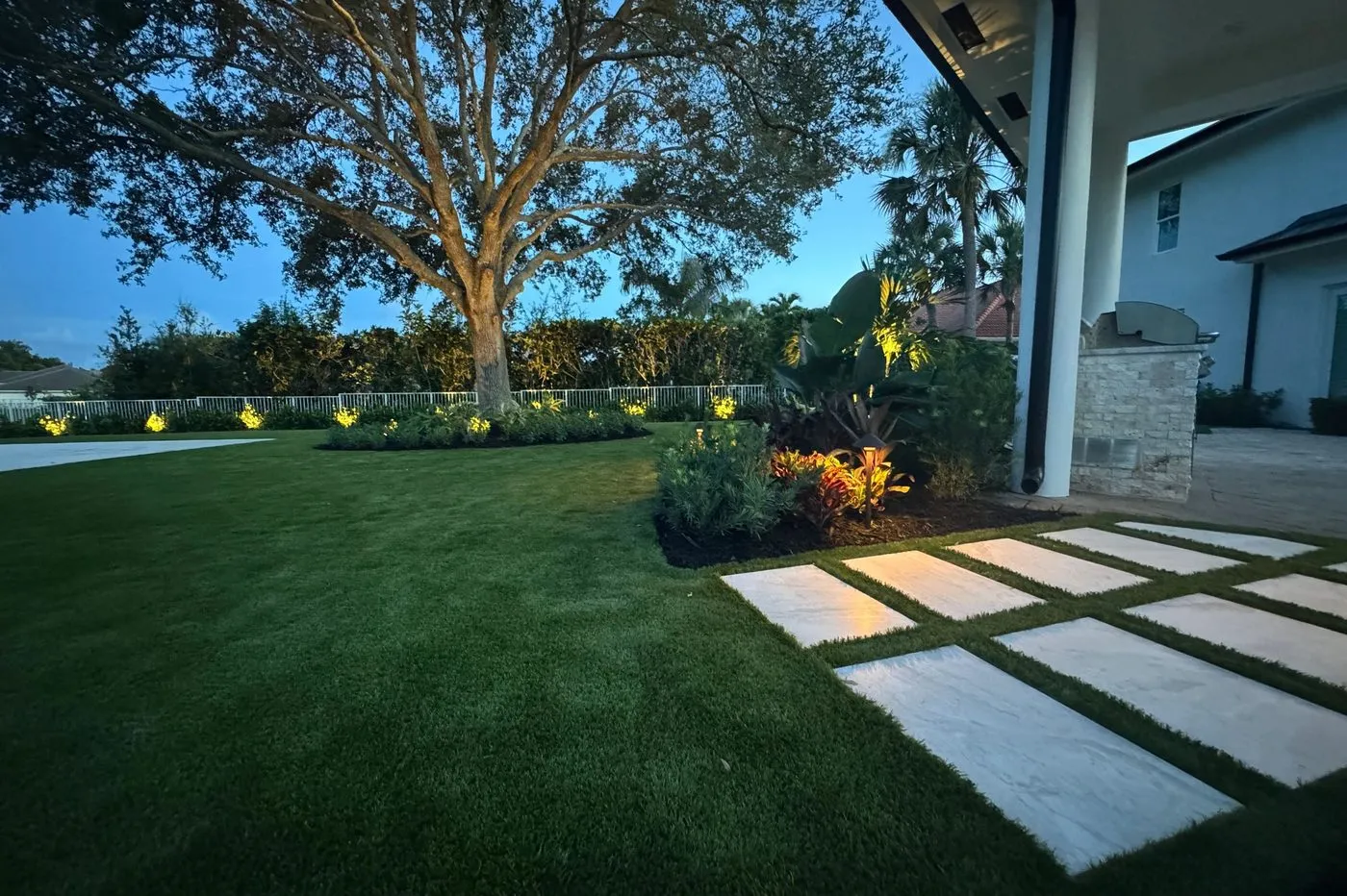 Large paver stepping stones set into a turf lawn alongside a house